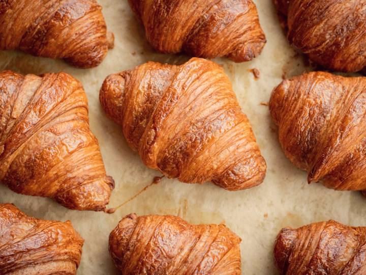 Rows of golden, flaky butter croissants on baking paper