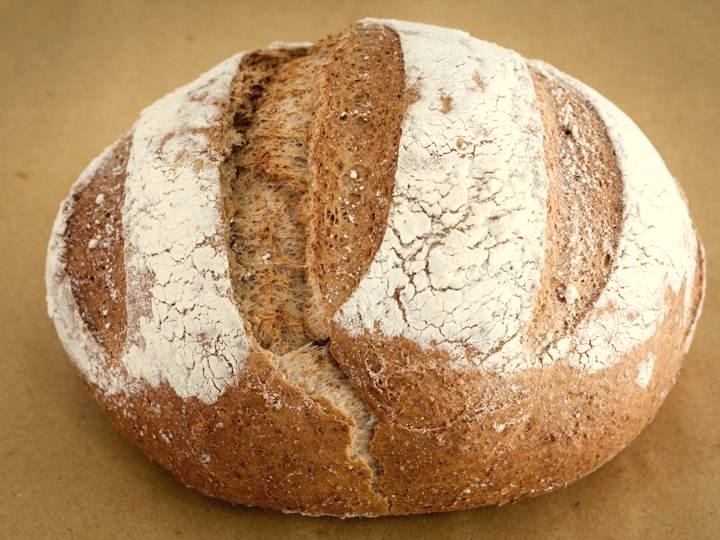 Round country sourdough loaf with a floured, scored crust
