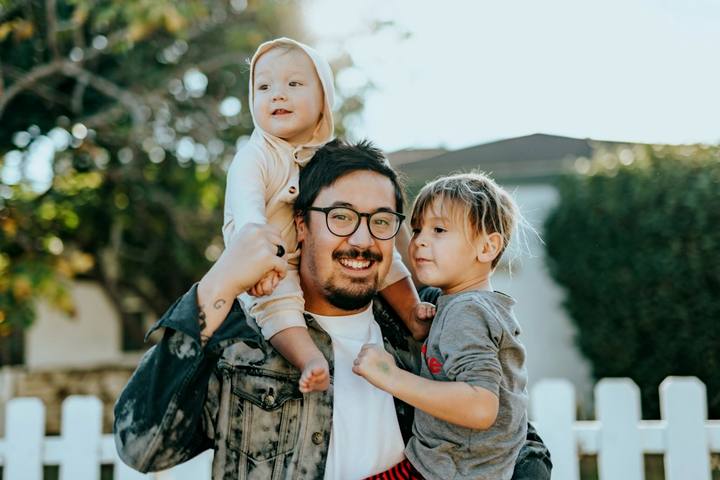 A father outdoors with his two young children