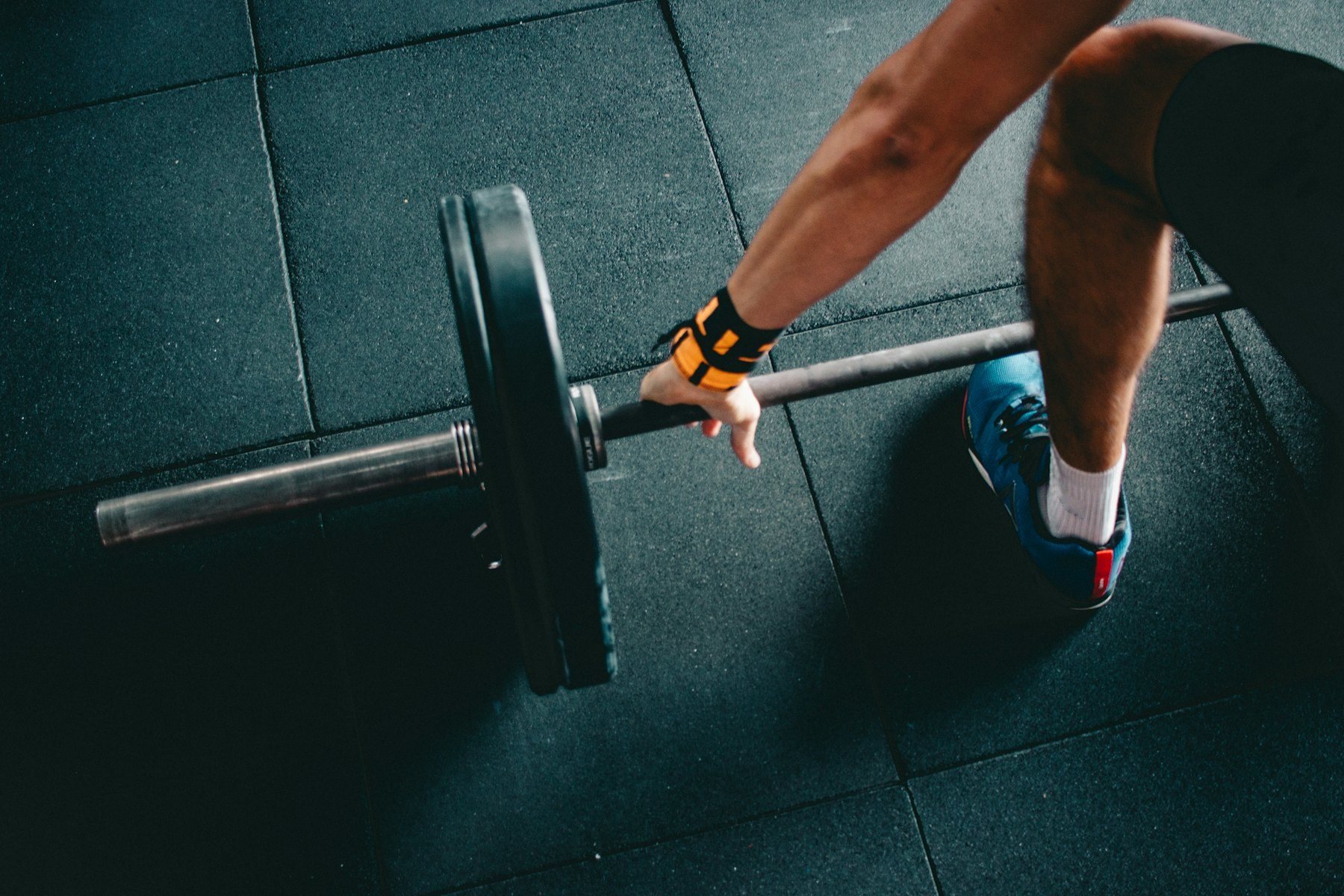 A lifter's chalked hand gripping a loaded barbell on the rubber floor