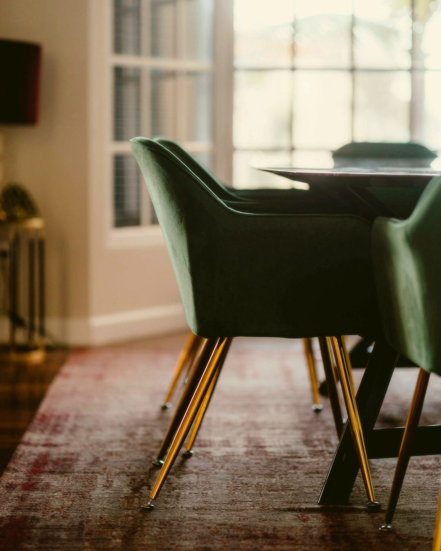 A green velvet dining chair on slender brass legs