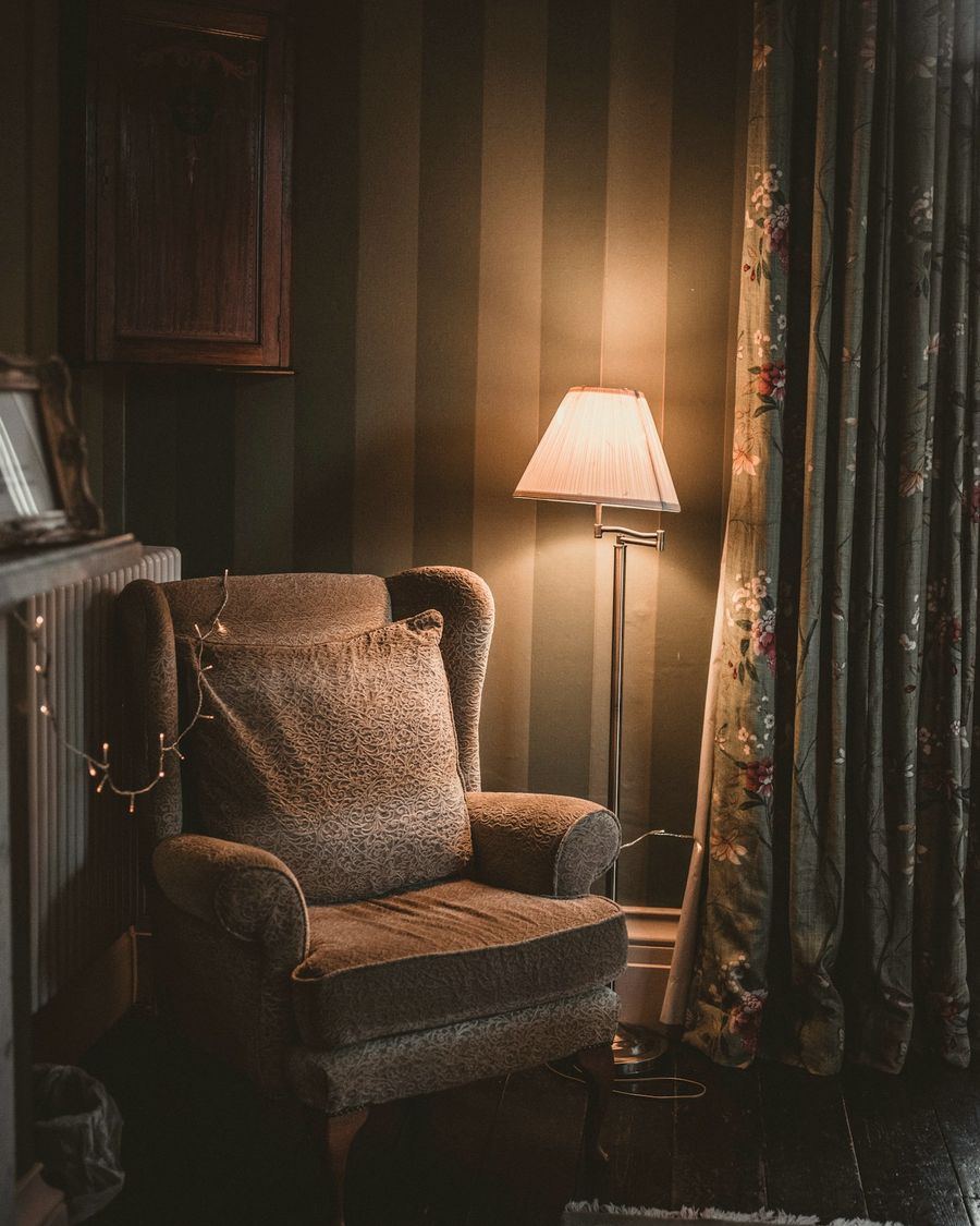 A deep club chair beside a standard lamp in a panelled room