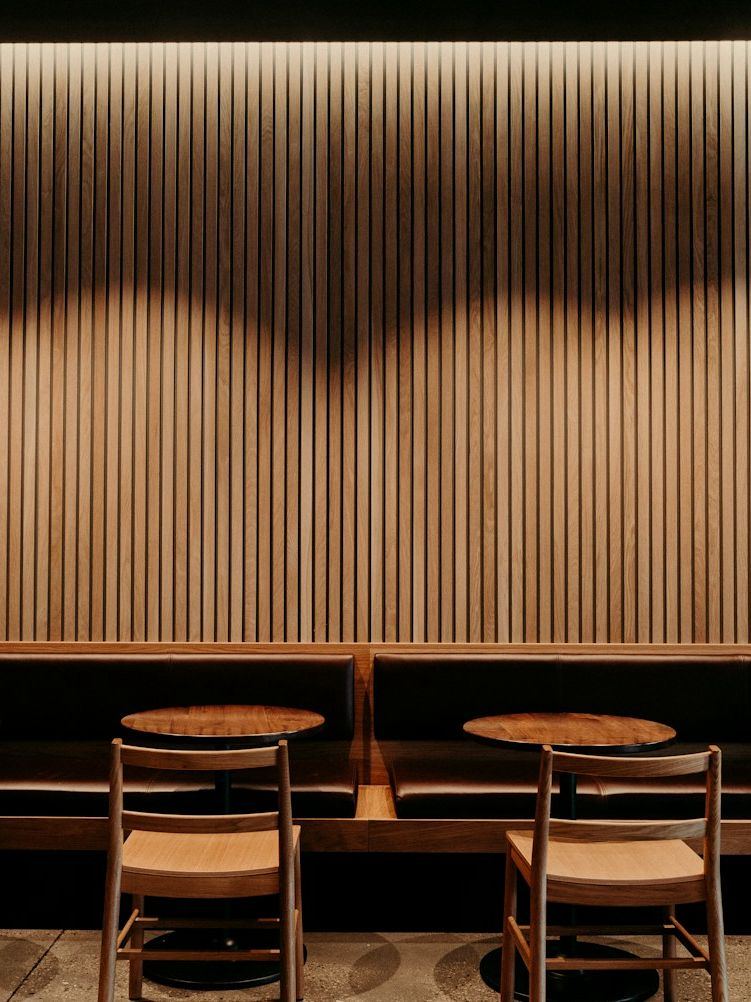 A lounge with a backlit fluted timber wall and a long banquette