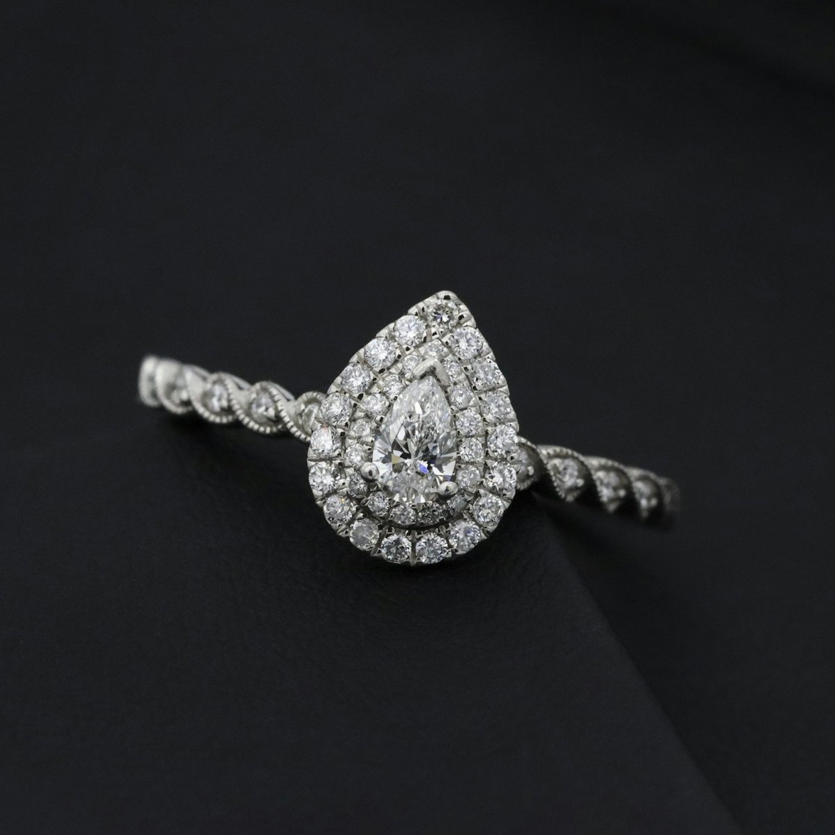 Pear-cut diamond ring with a double halo on black
