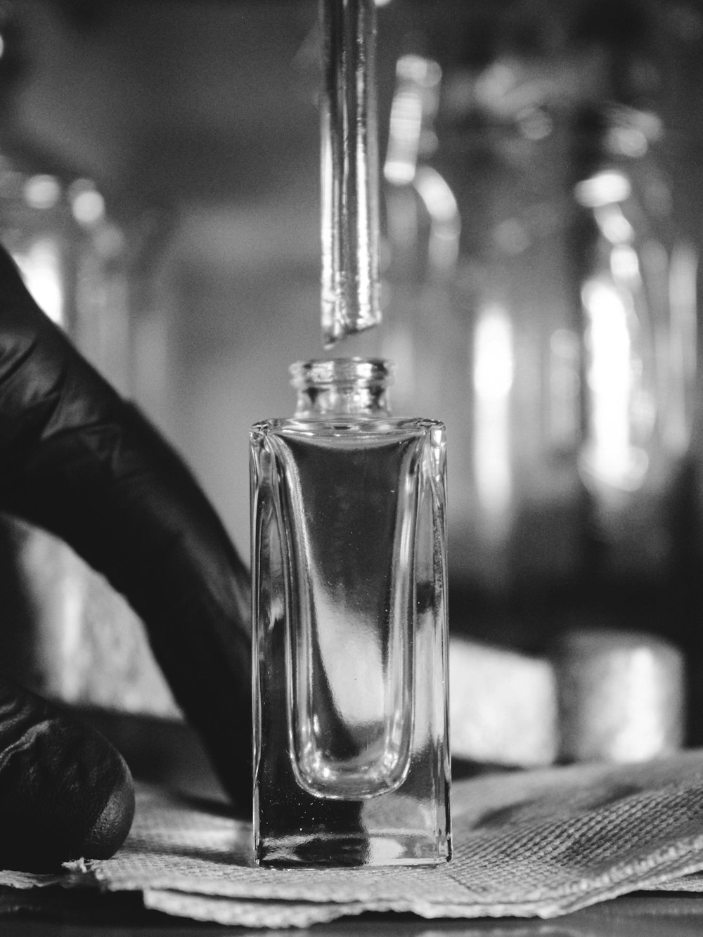 A perfumer filling a clear flacon with a pipette